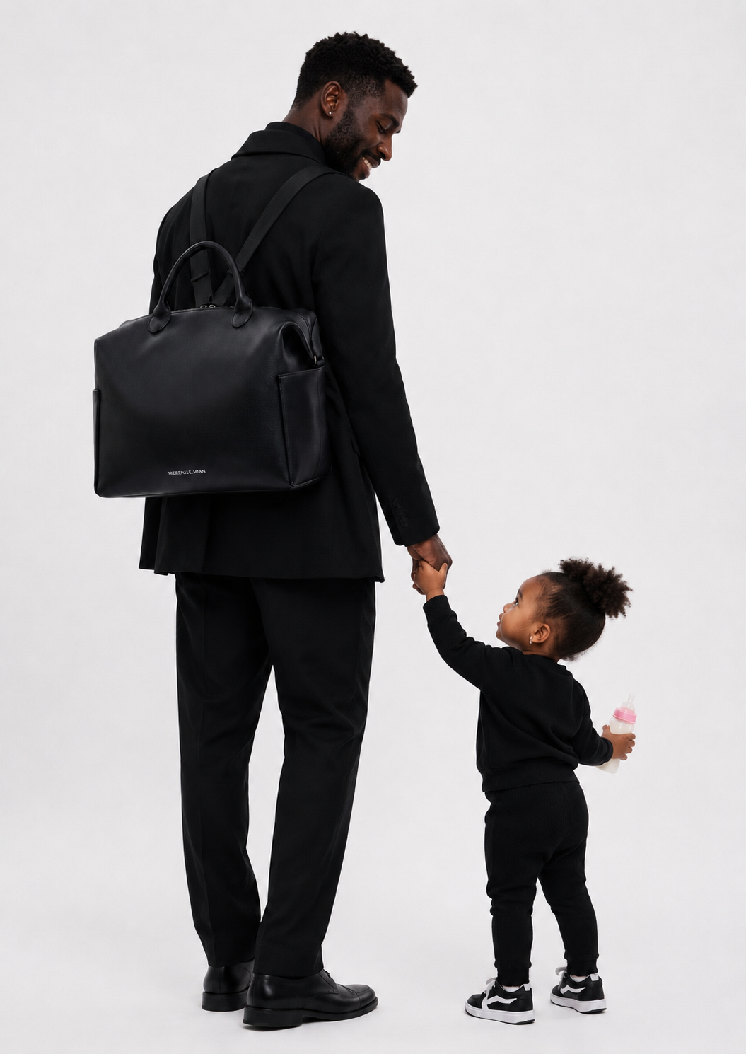 Father and toddler in all black with the bag on his shoulder