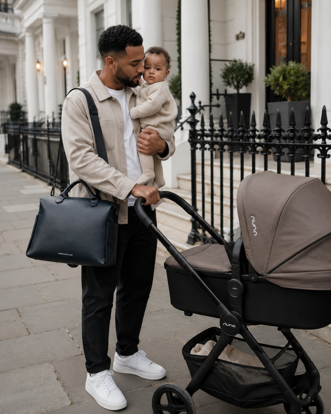 Father with baby beside a pram, bag on his shoulder